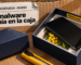Ilustración con una metáfora visual: sobre una pared de cartón corrugado de embalaje, una caja de celular azul oscuro abierta muestra un teléfono negro apagado en su bandeja; por debajo del teléfono asoma una ramita de mimosa amarilla y, en el borde de la caja, una etiqueta amarilla dice «PREINSTALADO». En primer plano, la tapa de la caja y un cúter. Arriba a la izquierda, en una etiqueta de envío, el logo de Bitdefender, el texto «Bitdefender · Android» y el titular «El malware venía en la caja».
